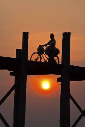 Frau schiebt ihr Fahrrad ueber die U-Bein-Bruecke ueber den Taungthaman-See bei Sonnenaufgang, Myanmar, Amarapura The BURMESE use the teak U BEIN BRIDGE to commute across the Taungthaman Lake at sunrise , Burma, Amarapura BLWS323196