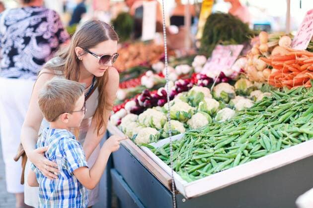 Mutter und Sohn kaufen gruene Erbsen an einem Gemuesestand mother and son buying green peas at a vegetable market BLWS313918