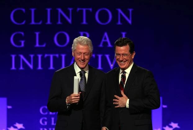 Television host Stephen Colbert (R) and former U.S. President Bill Clinton smile to the crowd following a interview during day 2 of the Clinton Global Initative at Washington University in St. Louis on April 6, 2013. The mission of the Clinton Global Initiative (CGI) is to turn ideas into action.  SLP2013040613