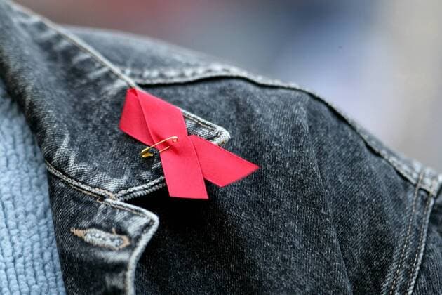 Die Rote Aids-Schleife ist an eine Jacke geheftet. Die Rote Schleife ( englisch Red Ribbon ) ist weltweit ein Symbol der Solidarität mit HIV-Infizierten und AIDS-Kranken. Sie wurde 1991 von der New Yorker Künstlergruppe Visual AIDS geschaffen. Aids-Schleife am Kragen