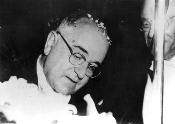 With his head covered with flower petals thrown by an enthusiastic crowd, Getulio Vargas, the new Brazilian President signs the official book of Brazilian Parliament after the ceremony of taking the oath at a recent ceremony in Rio de Janeiro. 7th February 1951 UnitedArchives00229578 