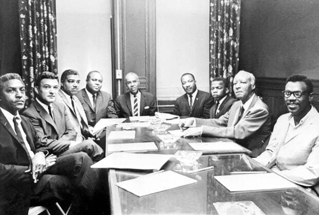 At a meeting here in NAACP Headquarters July 29th are L to R Bayard Rustin, Washington march leader, Jack Grennberg NAACP lawyer, Whitney M Young Jnr, National Urban League executive director, James Farmer National Core Director, Roy Wilkins executive secretary of the NAACP, the Rev Dr Martin Luther King Prseident of hte Southern Christian Leadership Conference, John Lewis Chairman of the Student Non-Violent Co-Ordinating Committee, A Philip Randolph, Head of Negro American Labour Council and Courtney Fox of the student group. Wilkins read a statement signed by himself, King, Young and Randolph asking members of the major civil rights organisations to observe a broad curtailment if not total moratorium on all mass demonstrations until after November 3rd Presidential elections. In addition, the statement was critical of Senator Goldwater, accusing him of having injected racism into the UnitedArchives00499831 