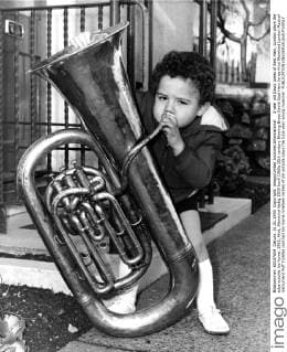 3 year old David Jones of East Ham, London plays the tuba outside his home. 1965, Kind, Kleinkind UnitedArchives00937597 