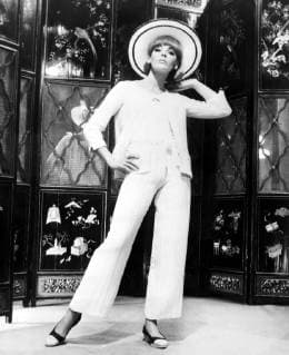 IMAGO ICONS: Coco Chanel Pure white ribbed silk and wool fabric for a pyjama suit with the skimmy look and pants widening at the hem presented by Chanel for summer resorts wear at fashion show on 9th April 1965  UnitedArchives01230269