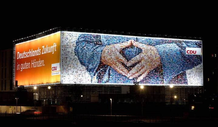 Feature - Am Washingtonplatz ziert an einem Baugeruest ein ueberdimensionales Wahlplakat der CDU mit dem Slogan Deutschlands Zukunft in guten Haenden und der typischen Handhaltung (Raute) der Angela Merkel. Das Bild ist aus vielen Einzelbildern zusammengesetzt worden. Bundestagswahl 2013 - Der Wahlabend der CDU im Konrad-Adenauer-Haus in Berlin, Deutschland am 22.09.2013.