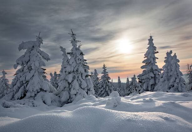 Sonne scheint durch Wolkendecke über verschneiter Landschaft