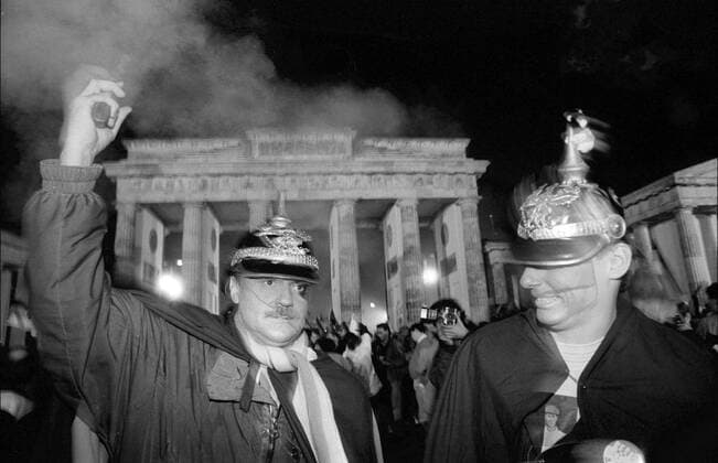 Feier zur Wiedervereinigung Deutschland, Berlin, 02.10.1990, Feier zur Wiedervereinigung am Abend des 2. Oktober am Brandenburger Tor: Männer mit Spitzhaube (Pickelhaube) und Pistole,