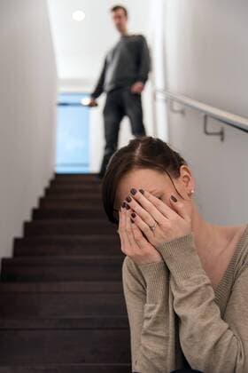 Junge Frau sitzt auf Treppe, häusliche Gewalt, Bedrohung Junge Frau sitzt auf Treppe, häusliche Gewalt, Bedrohung