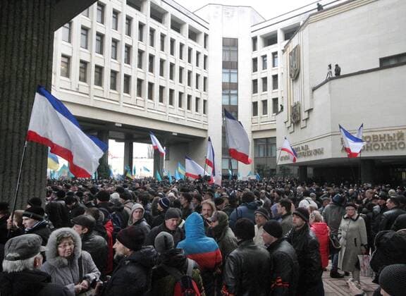 ITAR-TASS: SIMFEROPOL, UKRAINE. FEBRUARY 26, 2014. Demonstrators who rally against or in support of the new authorities of Ukraine hold three colour flags of the Autonomous Republic of Crimea and blue flags of Crimean Tatars. The groups oppose each other outside the Supreme Council of the Autonomous Republic of Crimea in Simferopol.  RE13B0FD