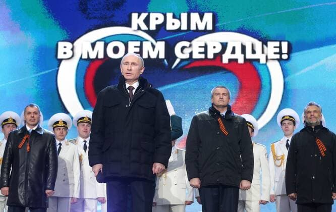 ITAR-TASS: MOSCOW, RUSSIA. MARCH 18, 2014. Russian president Vladimir Putin (front), Crimean Supreme Council chairman Vladimir Konstantinov (L back in black), Crimean Prime Minister Sergei Aksenov (C back in black), and Sevastopol head Alexei Chalyi (R in black) at a concert in Red Sqaure celebrating an interstate unification agreement between the Russian Federation, the Republic of Crimea and the city of Sevastopol. Under the terms of the agreement, the Republic of Crimea and Sevastopol become federal subjects of the Russian Federation.  RE13D2F5