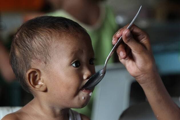 (140710) -- MANILA, July 10, 2014 (Xinhua) -- A boy eats during a non-government organization feeding program at a slum area in Manila, the Philippines, July 10, 2014. The population in the Philippines has a steady growth of 1.89 percent, ranking as the 12th most populated country in the world, with 100,617,630 in 2014. (Xinhua Rouelle Umali) PHILIPPINES-MANILA-POPULATION 