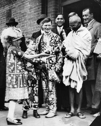 IMAGO ICONS: Mahatma Gandhi Sept. 15, 1931 - St. James, South Africa - MAHATMA GANDHI and The Pearly KING JAMES PHILLIP of Hoxton. Ghandi is presented with S.African oranges as a measure of his admiration as he left Kingsley Hall on route to The Indian Round Table Conference at St. James Palace. St. James South Africa  - ZUMAk09