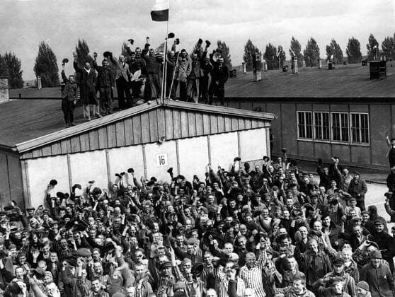 IMAGO History, Zweiter Weltkrieg: 1939 - 1945 Oct. 5, 1945 - Dachau, Bavaria, Germany - Dachau, the most infamous Nazi concentration camp of all has been liberated by men of the 42nd Rainbow Division of the U.S. 7th Army. Scenes of horror were witnessed by the American troops as they went from building to building. Thousands of starved corpses were piled nearly to the roof awating cremation. Many of the prisoners immediately seized the S.S. torturers and killed them, throwing their bodies into the moat surrounding the camp. Picture shows: Political prisoners cheer madly and even climb on the roof with flags of all nations which they had made secretly as they heard the guns of the 42nd Rainbow Division getting louder and louder on the approcach to Dachau. Dachau Germany  - ZUMAk09