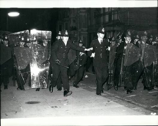 Aug. 08, 1977 - Violence Flares At The Notting Hill Carnival: Mobs of rioting youths clashed with the police during the Notting Hill Carnival last night, as the police moved in they were ment by a hail of beer cans, bottles, bricks and chair legs. By midnight the number of injured had reached 220 of which 90 were taken to hospital, some with stab wounds. Photo Shows: Police with the help of protective shields move in during the violence at Notting Hill last night.  - ZUMAk09