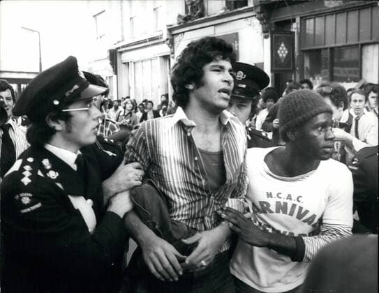 Aug. 08, 1977 - Violence Flares In The Notting Hill Carnival: Mobs of rioting youths clashed with the police during the Notting Hill Carnival last night as police moved in they were met with a hail of beer can and bottles, bricks and chair legs. By midnights the number of injured had reached 220, of which 90 were taken to hospital some with stab wounds. Photo Shows A Victim of the violence Stewards help Mr. Ahmed Harem from the crowd after he had been stabbed near Westway, Notting Hill during the Violence yesterday.  - ZUMAk09