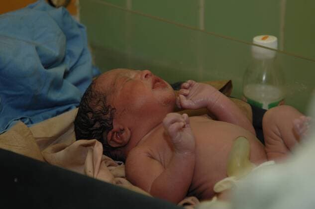 Midwife places a newborn baby onto a set of weighing scales