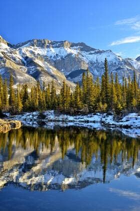 Miette mountain range in winter time reflected in the open waters of a warm spring in Jasper National Park, Alberta, Canada.  acp66541