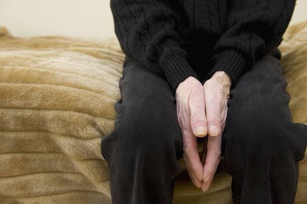 Senior man sitting on bed, close up model released  KN000473