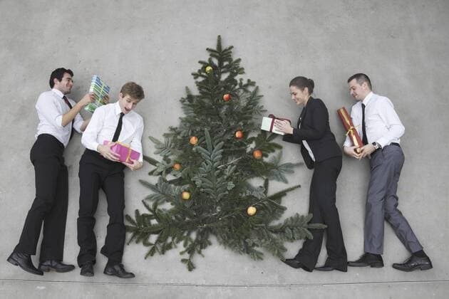 Four business people with Christmas presents standing round Christmas tree, elevated view model released  BAEF00065