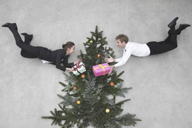 Businessman and businesswoman flying in front of christmas tree, holding presents, smiling, portrait, elevated view model released  BAEF00066