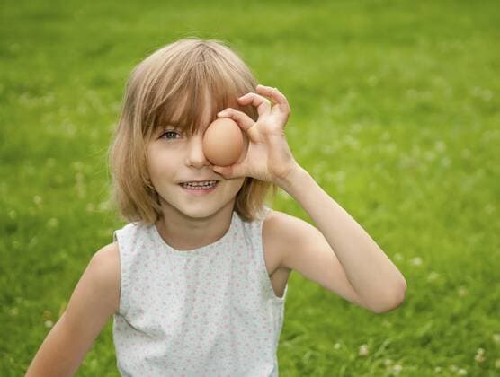 Germany, Brandenburg, Girl holding egg in front of eyes model released  BFRF000012