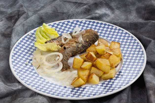 Fried herring with roasted potatoes and onions on a plate  CSF018790