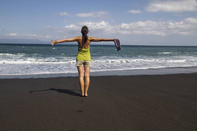 Indonesia. Young woman standing on black sand model released  MBEF000444