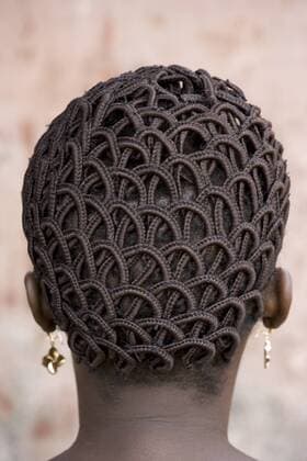A woman s head with braided patterned hair and earrings.  MINTxImages ArtxWolfe