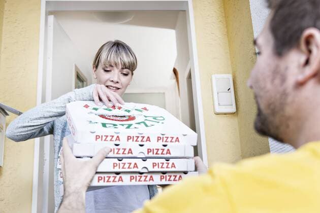 Germany, North Rhine Westphalia, Cologne, Young woman taking pizza boxes from delivery man, smiling model released property released  FMKYF000479