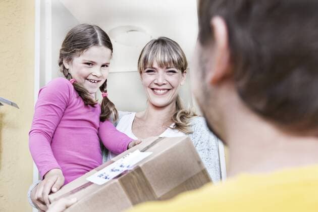 Germany, North Rhine Westphalia, Cologne, Mother and daughter taking letters from postman, smiling model released property released  FMKYF000508
