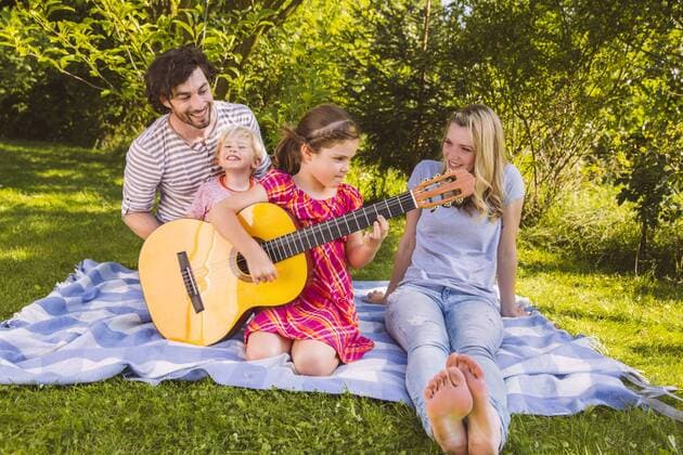 Family on picnic blanket playing guitar model released Symbolfoto property released  MFF001305