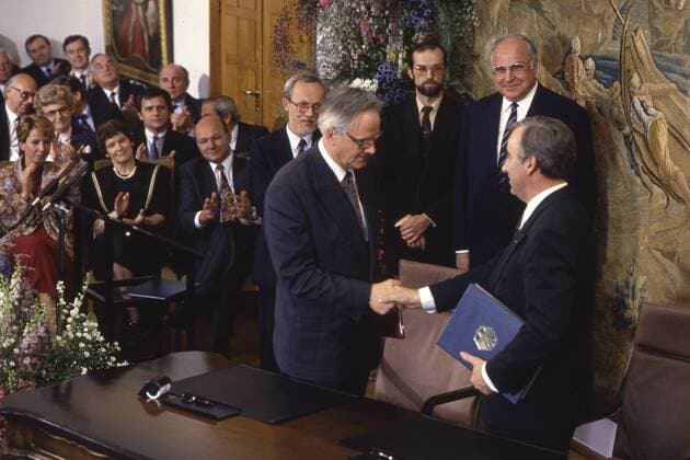 Bundesfinanzminister Theo WAIGEL, CSU, rechts, und Walter ROMBERG, Finanzminister der DDR, unterzeichnen den Staatsvertrag zur Waehrungs-, Wirtschafts- und Sozialunion, tauschen die Dokumente mit einem Handschlag aus, im Hintergrund beobachtet von Bundeskanzler Helmut KOHL, CDU, und Lothar de MAIZIERE, letzter Ministerpraesident der DDR, Bonn, 18.05.1990