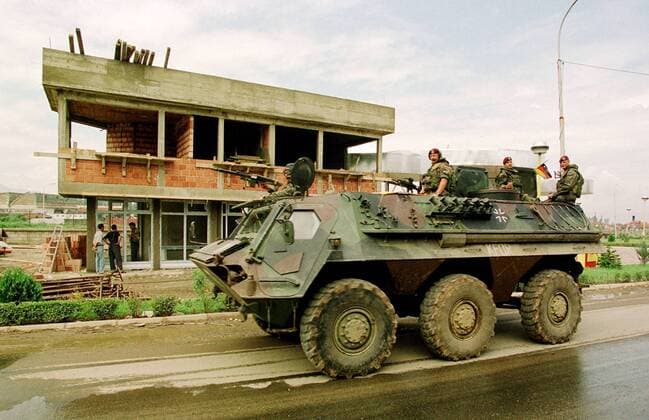 Kosovo Situation nach KFOR-Einmarsch Deutsche KFOR-Soldaten (Fallschirmjaeger) patroullieren in einem Schuetzenpanzer (Fuchs) durch Prizren. Im Hintergrund wird eine zerstoerte Tankstelle wieder aufgebaut. Prizren Jugoslawien, 30.7.1999