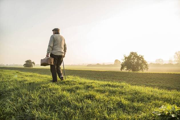 Senior man with bag walking in rural landscape model released Symbolfoto  UUF002731