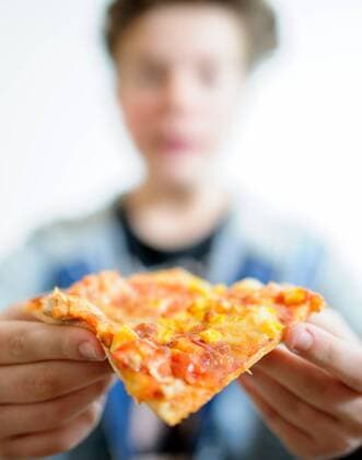 Ein Junge möchte in eine Pizza beißen, aufgenommen am 06.01.2015 in Dresden.