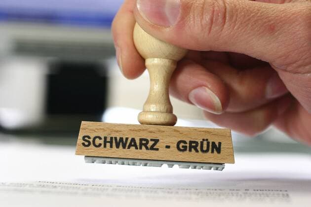 Laut Politbarometer ist Schwarz-Grün die beliebteste Koalition in Deutschland - Fotomontagen Stempel in der Hand mit der Aufschrift schwarz-gruen hand with a stamp schwarz-gruen, black-green BLWS165670