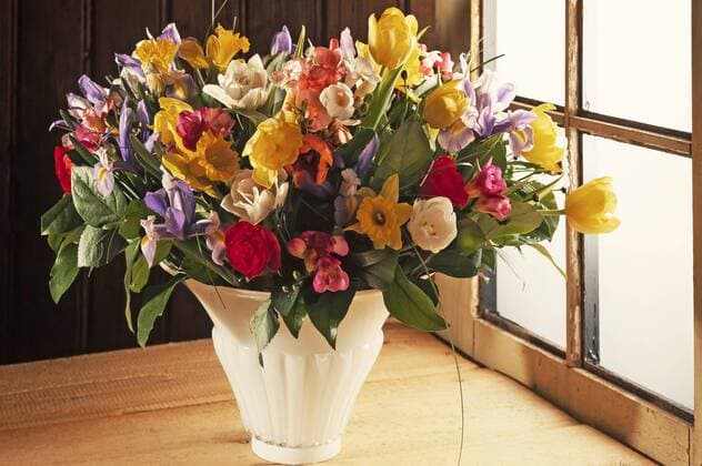  Bunter Frühlingsstrauß in einer Vase vor einer Holzwand am Fenster ibxmzc04093726.jpg