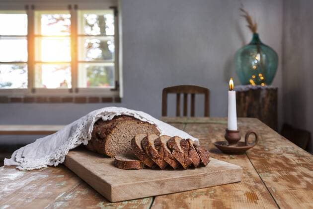 Home-baked bread on wooden board and lighted candle on wood table property released  JAAF000011