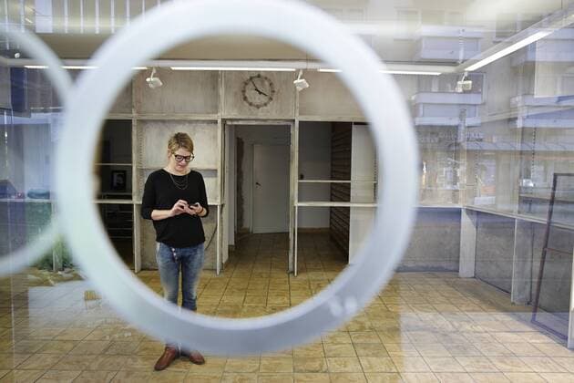Woman standing in empty shop holding cell phone model released Symbolfoto property released  EDF000122