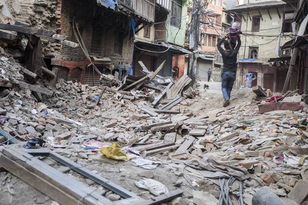 KATHMANDU, NEPAL - APRIL 26: (CHINA OUT) A man holding a child high passes by the ruins on April 26, 2105 in Kathmandu, Nepal. A 8.1-magnitude earthquake struck Nepal on Saturday and the earthquake felt in southeast China s Tibet Autonomous Region which brought some houses into collapse. While another 7.1-magnitude earthquake hit the county again the following day afternoon. Chinese government sent out Sichuan Rescue Team, the only one national emergency medical rescue team who could settle camps above an altitude of 3500 meters, to Nepal to support local rescue work and international assistance were also sent to the disaster areas. The earthquake had caused at least 3218 people to death and parts of Chinese visitors were detained in Nepal by Monday morning.  CFP466626281