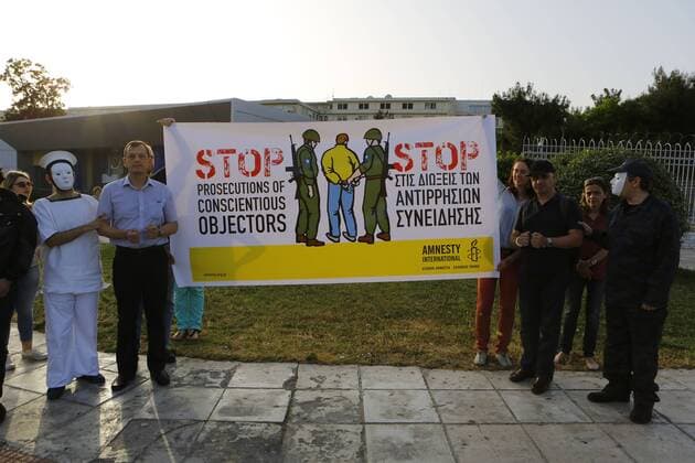 May 15, 2015 - Athens, Attica, Greece - Protesters stand outside the Ministry of Defense, calling for an end of the prosecution of conscientious objectors. Activists protested outside the Greek Ministry of Defense, calling for an end to the prosecution of conscientious objectors on the International Day of Conscientious Objectors. A large Peace sign with torches was created in Athens in the Evening. Athens Greece - ZUMAp133