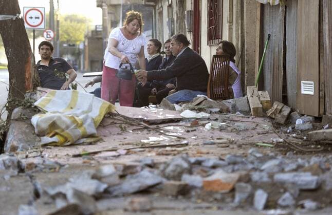 CONCEPCION, Chile - People sit in front of a building next to rubble on March 3, 2010, in Concepcion, Chile. The death toll from the Feb. 27 earthquake rose to over 800.  0304015