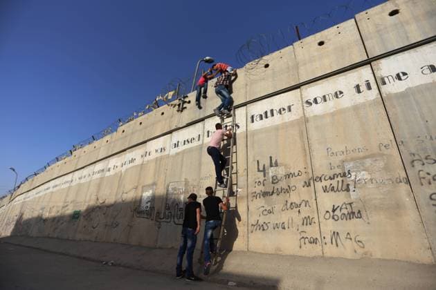 Palestinian men climb a section of Israeli separation wall near the West Bank city of Al-Ram which is located between Ramallah and Jerusalem, on their way to Al-Aqsa Mosque for Friday Prayers in the first week of Ramadan, on June 19, 2015. ) MIDEAST-AL-RAM-FRIDAY-PRAYERS FadixArouri 