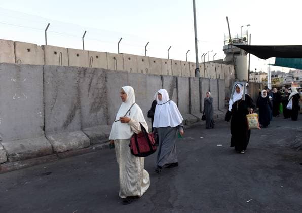 Palestinian Moslems wait next to the Israeli separation wall at the Qalandia Checkpoint, West Bank, on their way to pray at the Al-Aqsa Mosque in Jerusalem on the final Friday of Ramadan, July 10, 2015. Moslems around the world celebrate the holy month of Ramadan by refraining from eating, drinking, smoking and not performing sexual relations from dawn until dusk.  JER2015071001 DEBBIExHILL