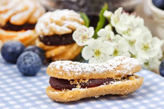 Eclairs with blueberry marmalade. Blooming apple twig in the background  KantarukxAgnieszka bew18D3CE3