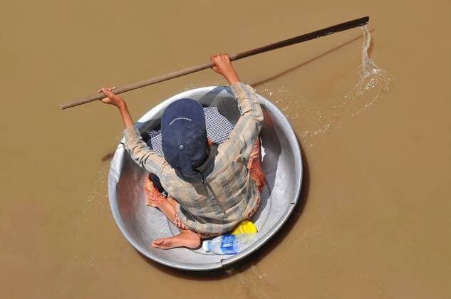 Cambodia, Siem Reap, Young boy using a bowl to float around the boats in the lake at Floating Village of Chong Kneas, Tonle Sap  WojtkowskixCezary bew1A42673