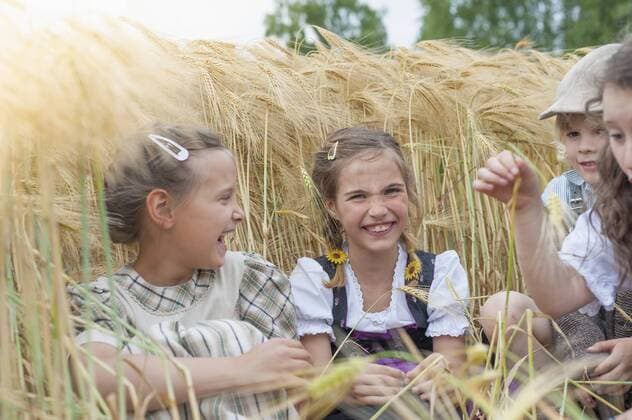 Germany, Saxony, children sitting in a grain field having fun model released Symbolfoto  MJF001584