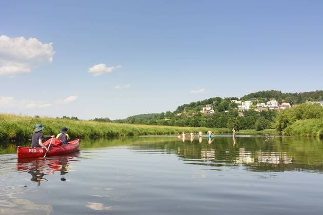 Paddler in Kanu (Kanadier) auf dem Fluss Regen und badende Jugendliche mit Fahrrad im Wasser in Cham, Oberpfalz, Bayern, Deutschland model released