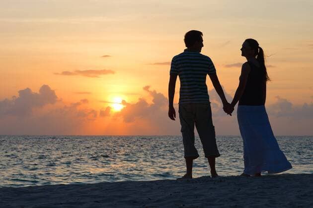 ein Paar am tropischen Strand geniesst den Sonnenuntergang couple on tropical beach enjoying the sunset BLWS269801