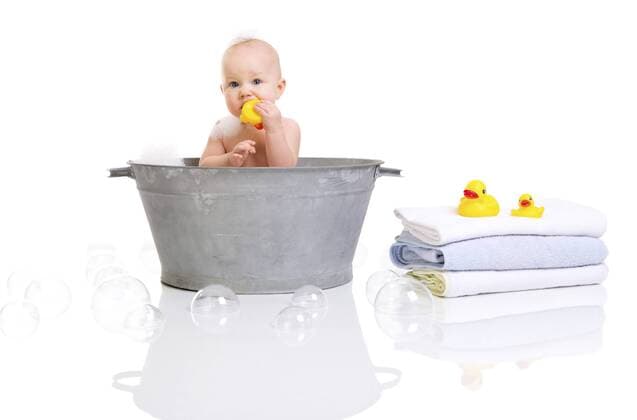 kleines Baby sitzt in einer Waschschuessel und badet mit einer Quietscheente Bath Time. Cute happy baby girl having bath BLWS233203